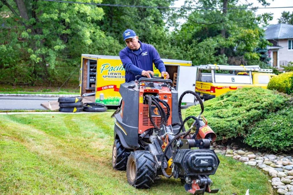 A Pacific Lawn Sprinkler technician operates a trenching machine to install a system on
