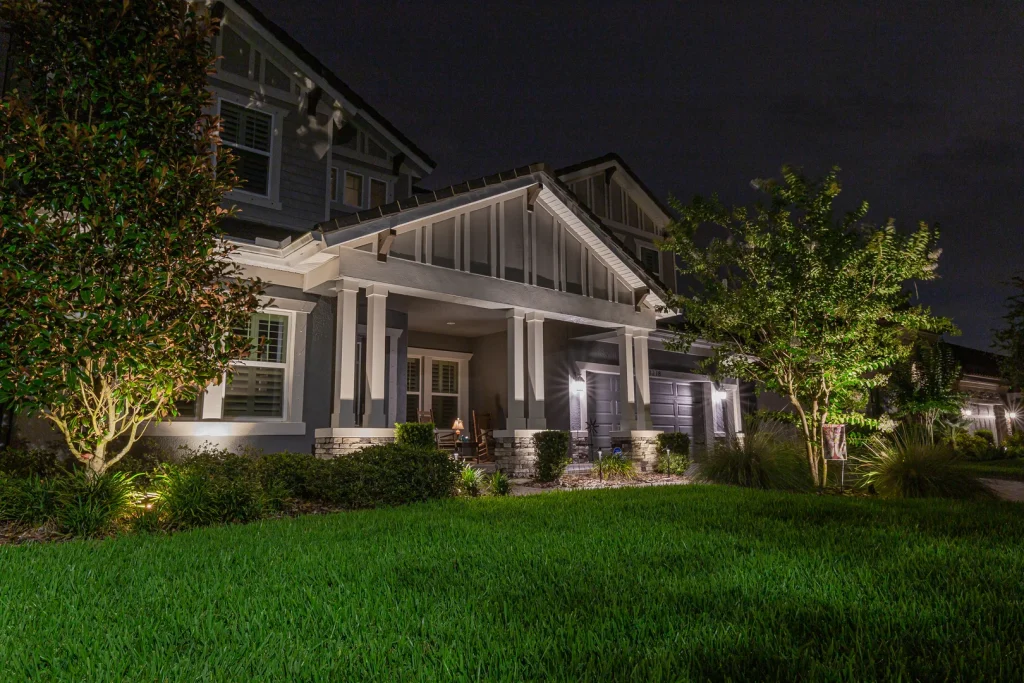 A modern house at night with illuminated landscaping and a welcoming front porch.